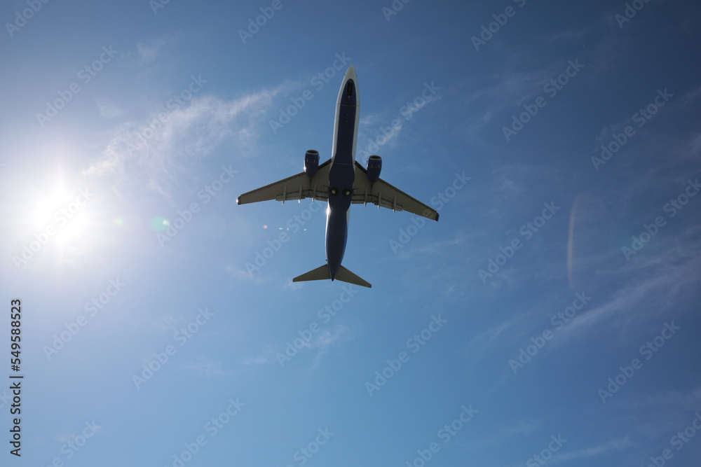 Fototapeta premium Modern white airplane flying in sky, bottom view