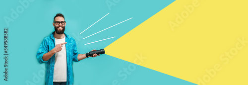 Young bearded hipster man holding a flashlight. Your text here. Discounts, sales, seasonal sales. Colorful summer concept. Modern creative artwork.