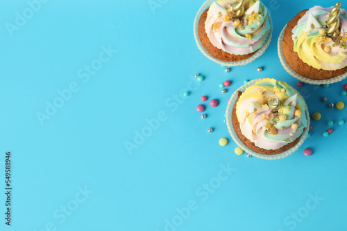 Cute sweet unicorn cupcakes on light blue background, flat lay. Space for text