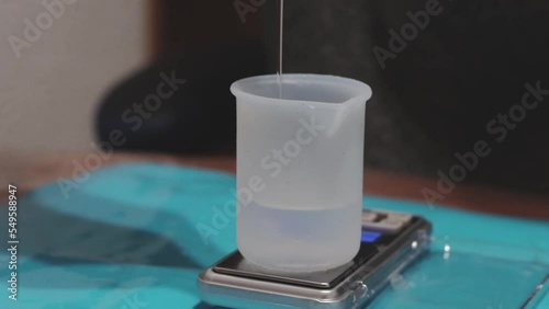 person weighing epoxy resin into a vessel