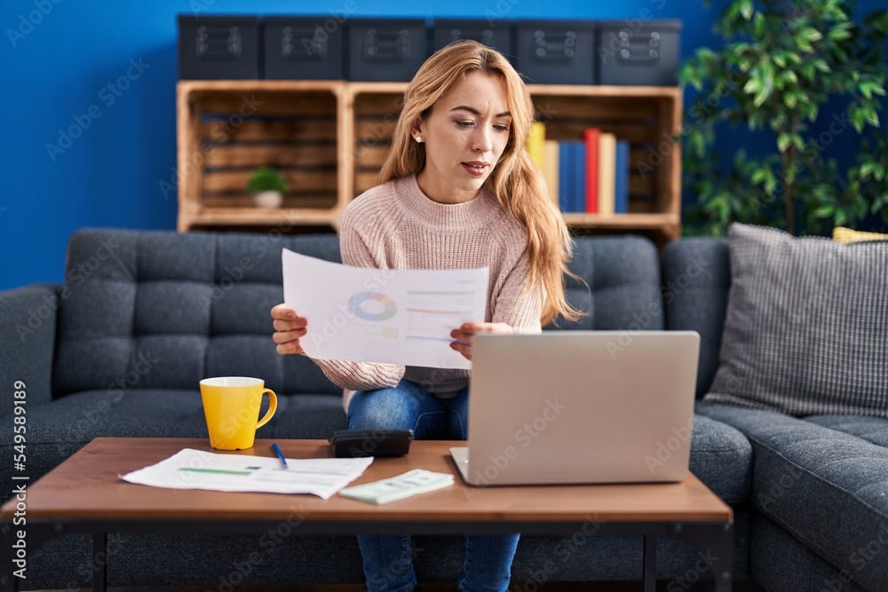Fototapeta premium Young woman sitting on sofa accounting at home