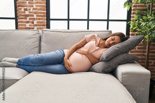 Young latin woman pregnant sleeping on sofa at home