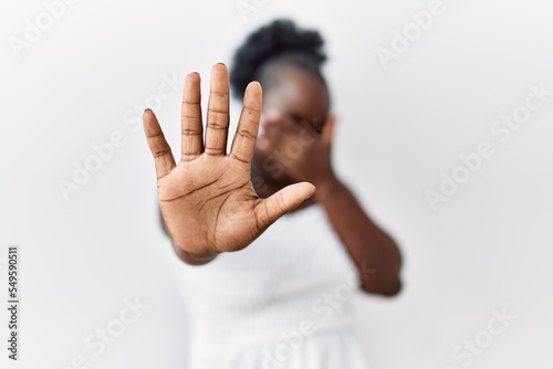 Young african woman standing over white isolated background covering eyes with hands and doing stop gesture with sad and fear expression. embarrassed and negative concept. photo