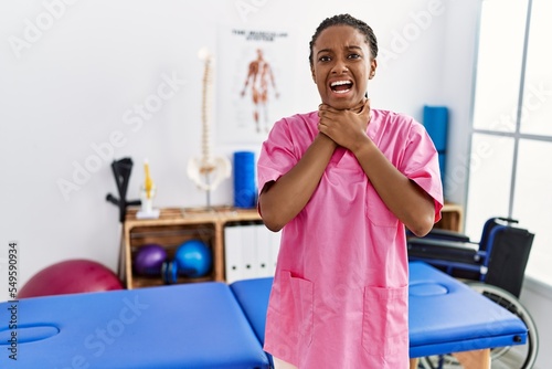 Young african american woman working at pain recovery clinic shouting and suffocate because painful strangle. health problem. asphyxiate and suicide concept.
