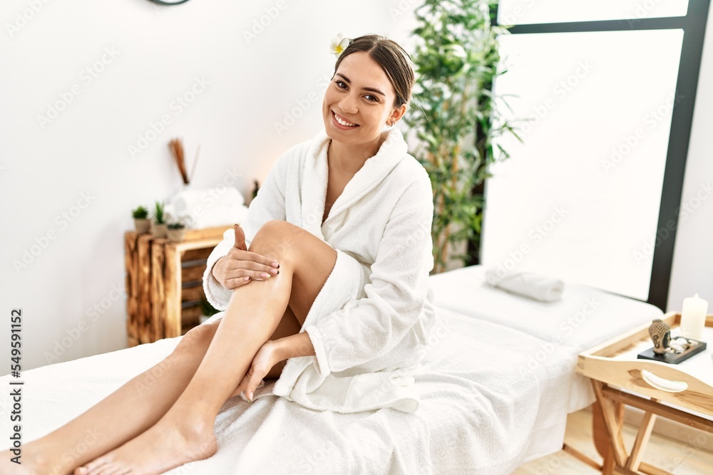 Young hispanic woman smiling confident using cream at beauty center. Young hispanic woman smiling confident using cream at beauty center.