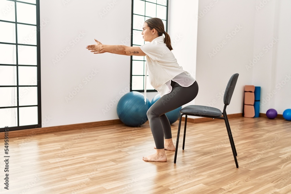 Young hispanic woman stretching at sport center. Young hispanic woman stretching at sport center.