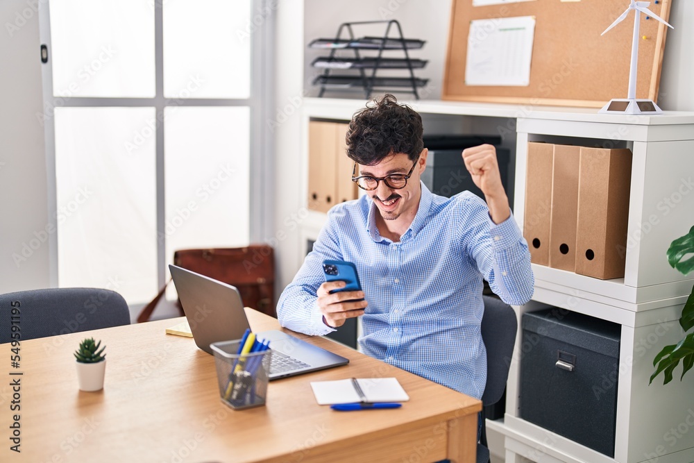Young caucasian man business worker using smartphone with winner expression at office Young caucasian man business worker using smartphone with winner expression at office