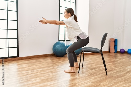 Young hispanic woman stretching at sport center.