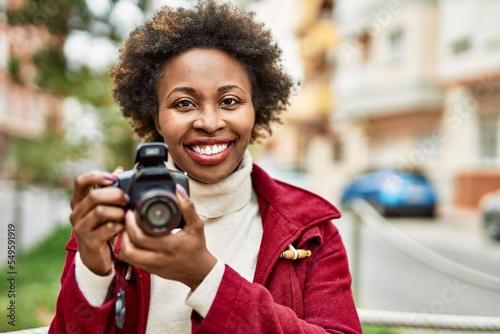 Young african american woman holding dslr camera at the city © Krakenimages.com
