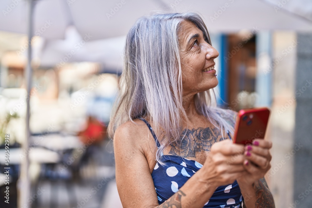 Middle age grey-haired woman smiling confident using smartphone at street Middle age grey-haired woman smiling confident using smartphone at street