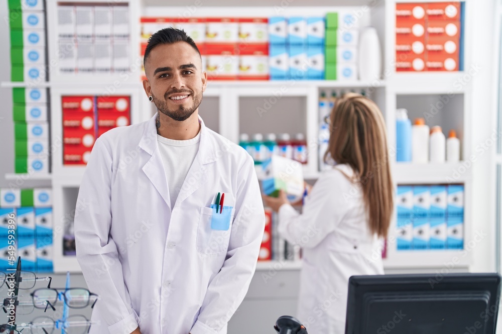 Man and woman pharmacist smiling confident standing at pharmacy