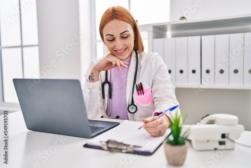 Young caucasian woman doctor using laptop writing medical report at clinic