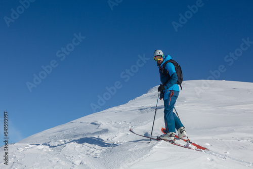 An active ski-tour rider on a winter trail in the middle of the mountain range