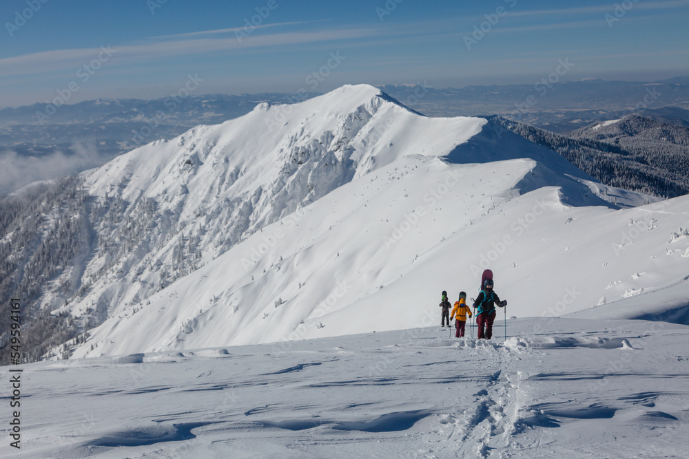 A team of free-riders climbs together into snowy mountains