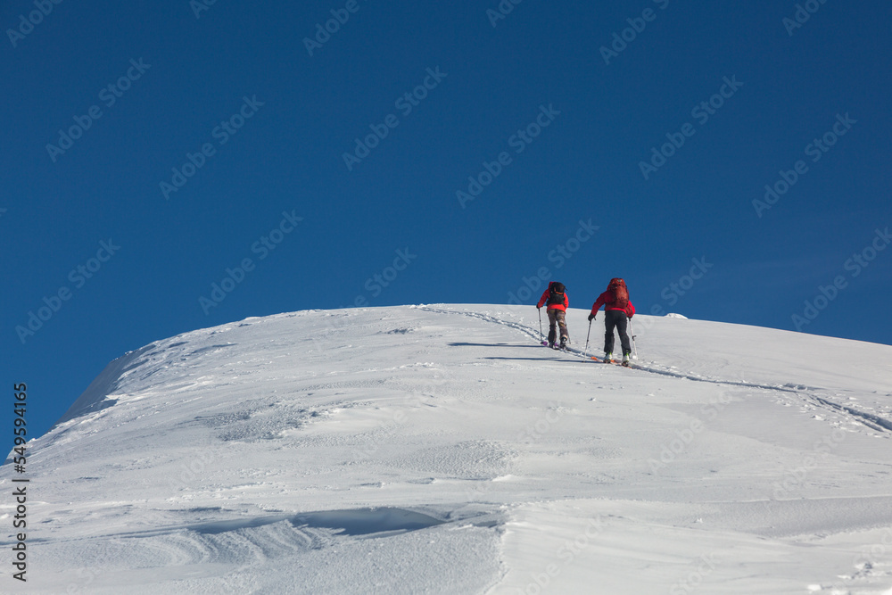 A team of skitour freeriders climbs together into snowy mountains