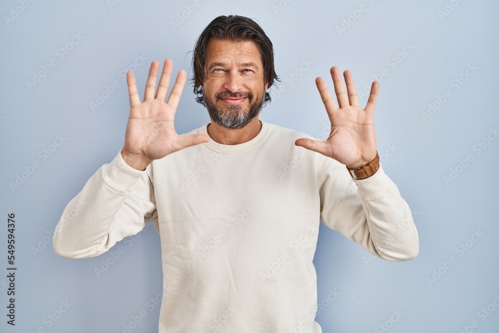 Handsome middle age man wearing casual sweater over blue background showing and pointing up with fingers number ten while smiling confident and happy. Handsome middle age man wearing casual sweater over blue background showing and pointing up with fingers number ten while smiling confident and happy.
