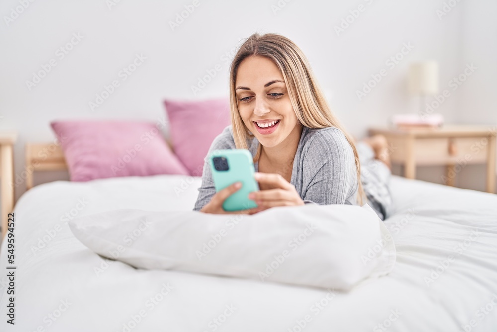 Young woman using smartphone lying on bed at bedroom Young woman using smartphone lying on bed at bedroom