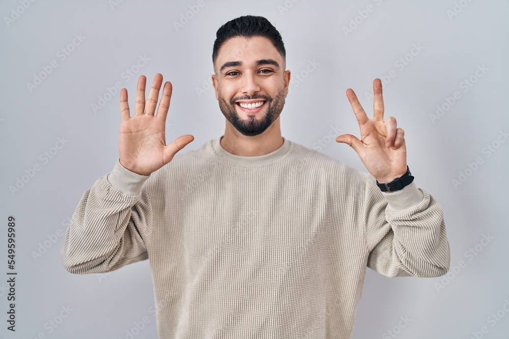 Young handsome man standing over isolated background showing and pointing up with fingers number eight while smiling confident and happy. Young handsome man standing over isolated background showing and pointing up with fingers number eight while smiling confident and happy.