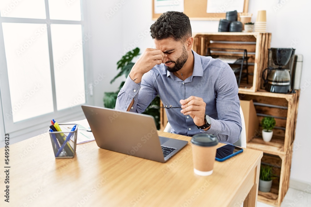 Young arab man stressed using laptop working at office Young arab man stressed using laptop working at office
