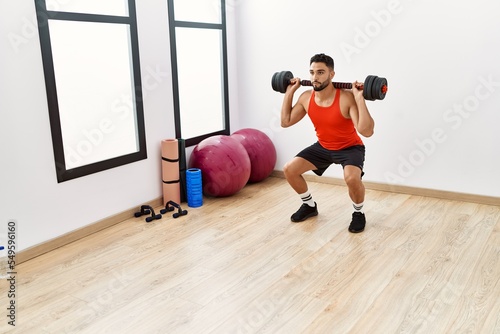 Young arab man training with dumbbells at sport center