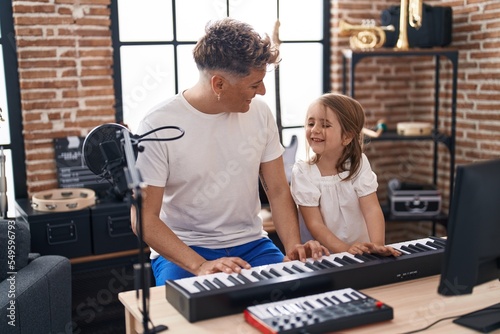 Father and daughter playing piano keyboard at music studio © Krakenimages.com