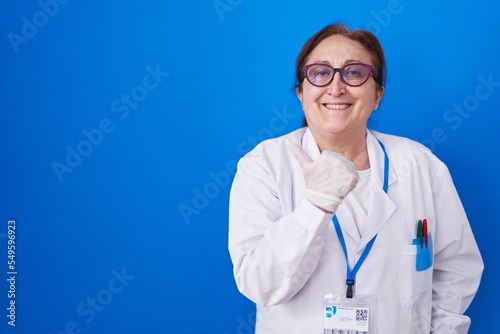 Senior woman with glasses wearing scientist uniform smiling happy and positive  thumb up doing excellent and approval sign