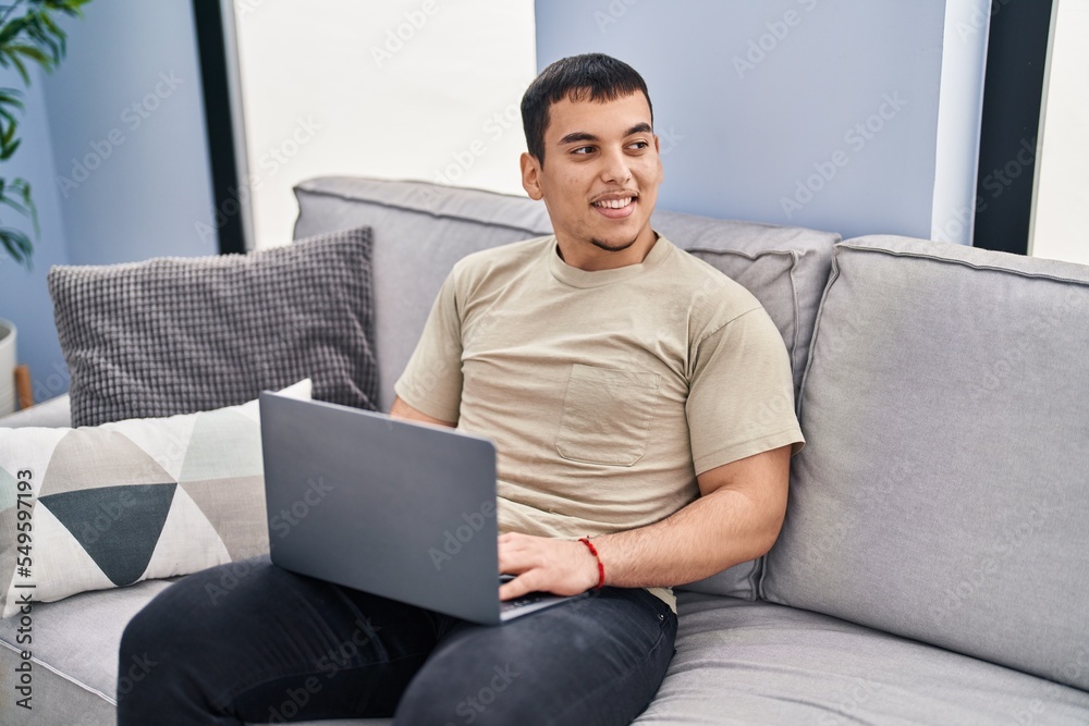 Young man using laptop sitting on sofa at home Young man using laptop sitting on sofa at home