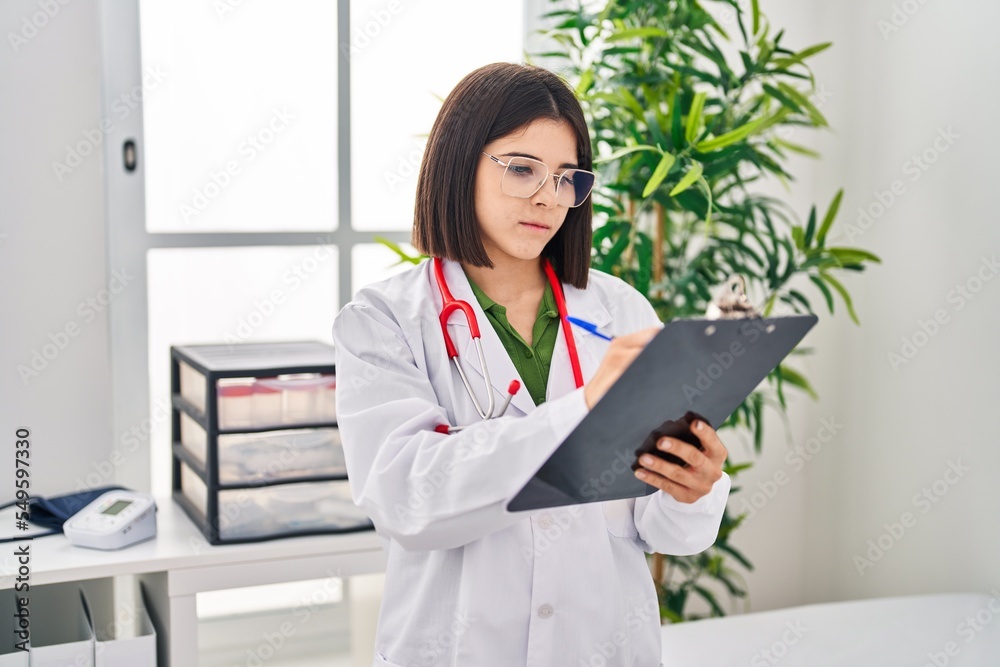 Young beautiful hispanic woman doctor writing medical report at clinic Young beautiful hispanic woman doctor writing medical report at clinic