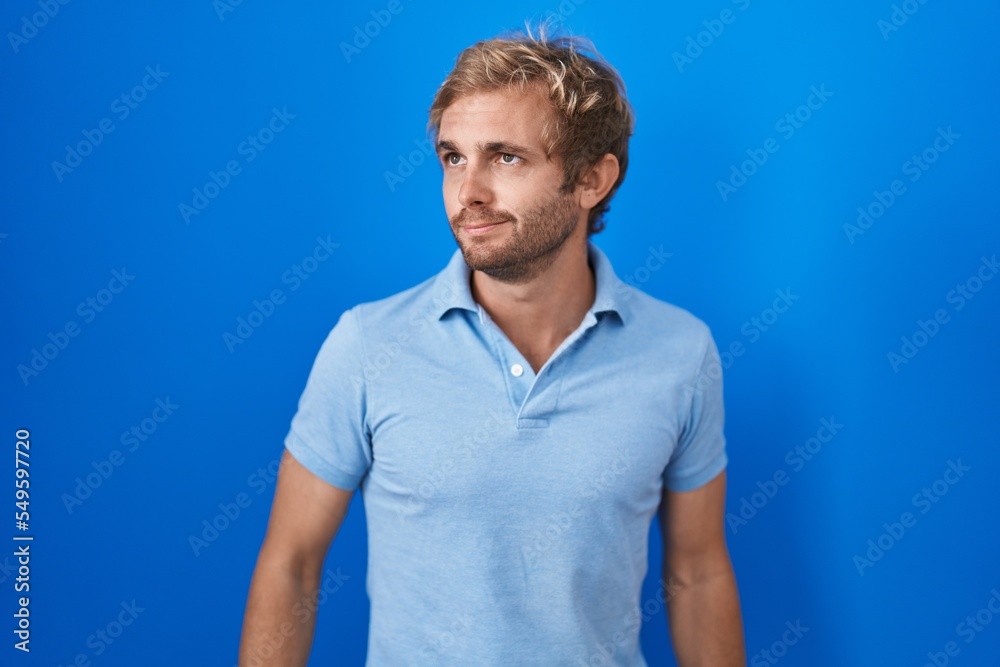 Caucasian man standing over blue background smiling looking to the side and staring away thinking. Caucasian man standing over blue background smiling looking to the side and staring away thinking.