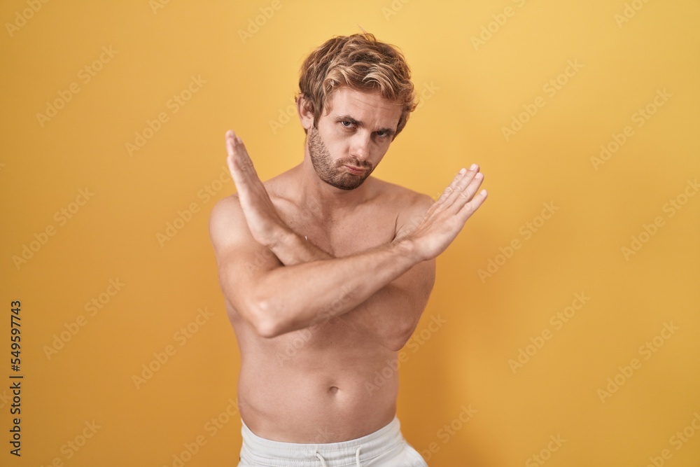 Fototapeta premium Caucasian man standing shirtless wearing sun screen rejection expression crossing arms doing negative sign, angry face