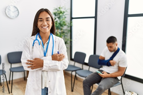 Young asian doctor woman at waiting room with a man with a broken arm happy face smiling with crossed arms looking at the camera. positive person.