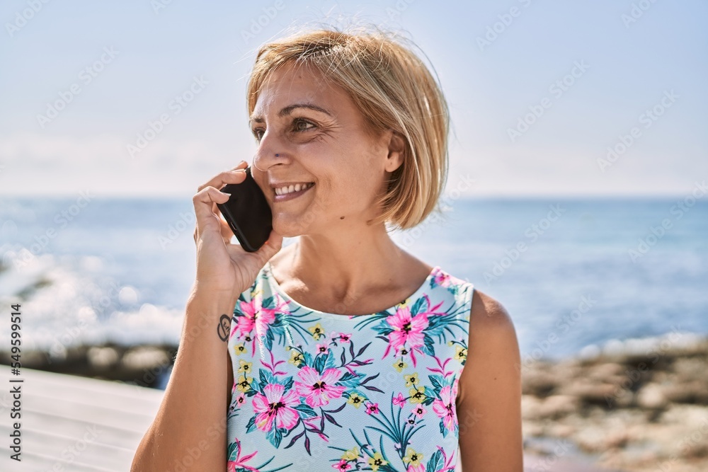 Middle age beautiful woman talking to the phone by the sea Middle age beautiful woman talking to the phone by the sea