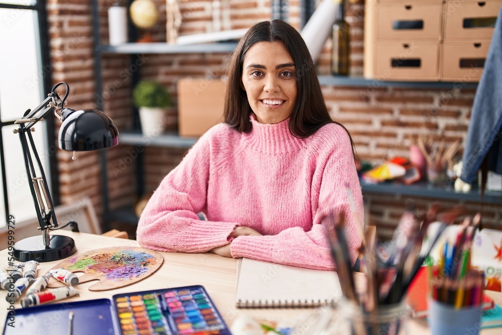 Fototapeta premium Young hispanic woman smiling confident drawing on notebook at art studio