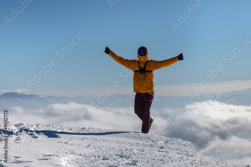 Happy hiker enjoys the view on cliff edge top of the winter mountain