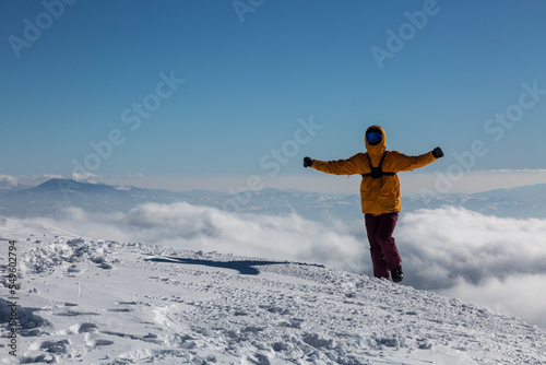 Happy hiker enjoys the view on cliff edge top of the winter mountain