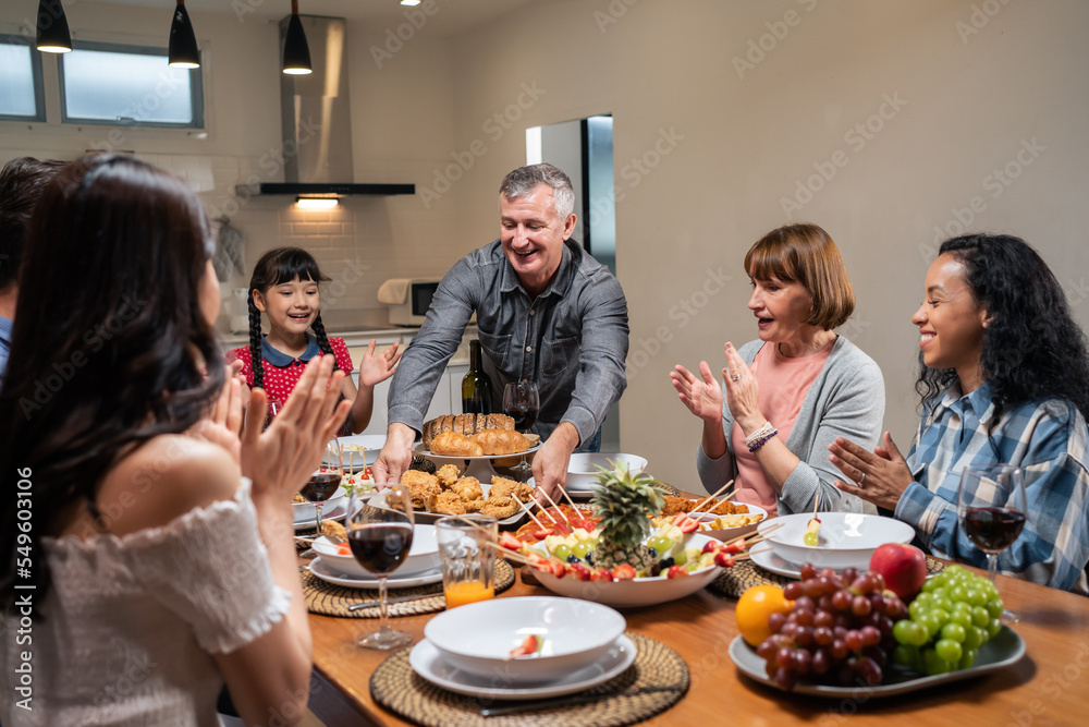 Multi-ethnic big family having dinner, enjoy evening party in house.