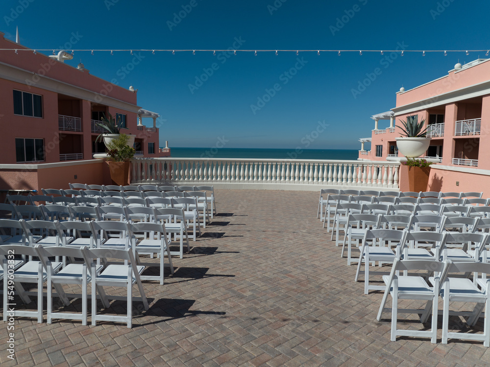 White chairs lined in rows at a beautiful rooftop wedding venue with blue sky