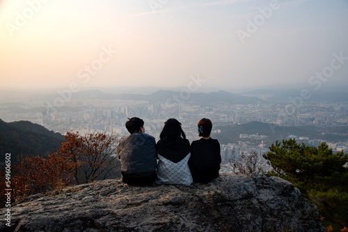 Three friends sitting on a rock at the top of the mountain
