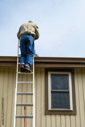 Senior man climbing an aluminum extension ladder to a home rooftop  © knelson20