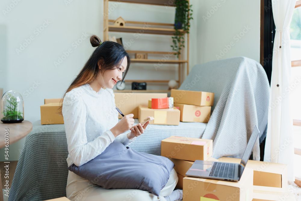 Starting small business entrepreneur of independent young Asian woman online seller is using computer and taking orders to pack products for delivery to customers. SME delivery concept Starting small business entrepreneur of independent young Asian woman online seller is using computer and taking orders to pack products for delivery to customers. SME delivery concept