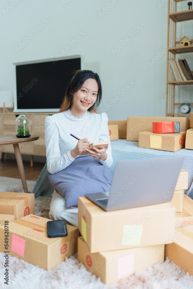 Starting small business entrepreneur of independent young Asian woman online seller is using computer and taking orders to pack products for delivery to customers. SME delivery concept Starting small business entrepreneur of independent young Asian woman online seller is using computer and taking orders to pack products for delivery to customers. SME delivery concept