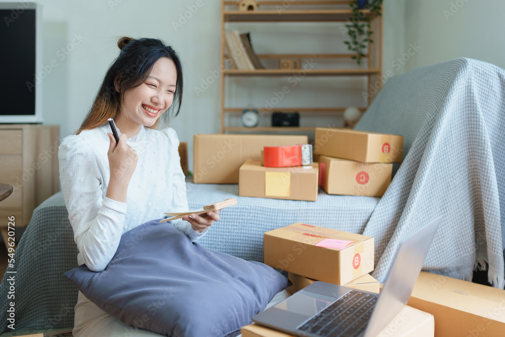 Starting small business entrepreneur of independent young Asian woman online seller is using computer and taking orders to pack products for delivery to customers. SME delivery concept Starting small business entrepreneur of independent young Asian woman online seller is using computer and taking orders to pack products for delivery to customers. SME delivery concept