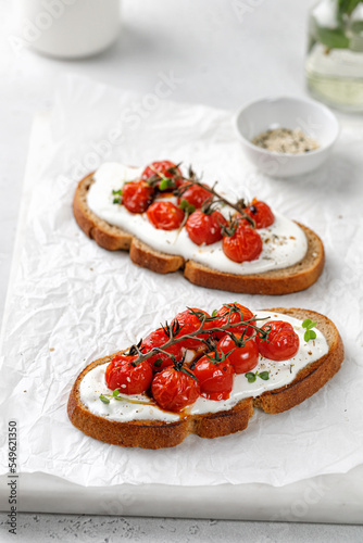 Healthy vegetarian sandwiches with whole grain bread. Toast, snack, bruschetta with ricotta cheese, cream cheese and baked tomatoes cherry.