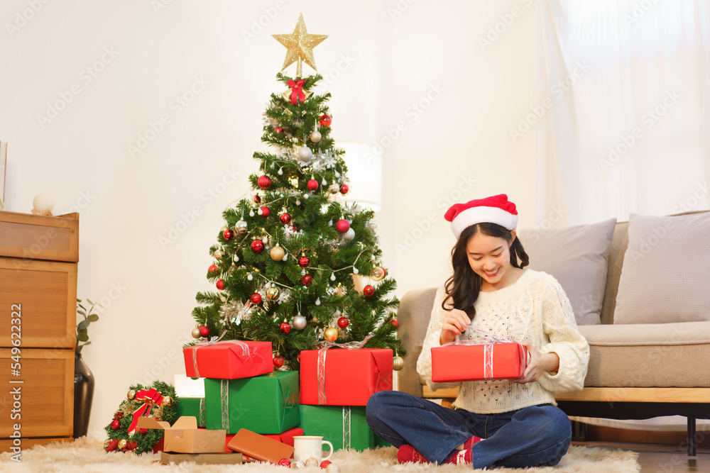 Christmas concept, Asian woman sitting in christmas decorated living room and open christmas gift Christmas concept, Asian woman sitting in christmas decorated living room and open christmas gift