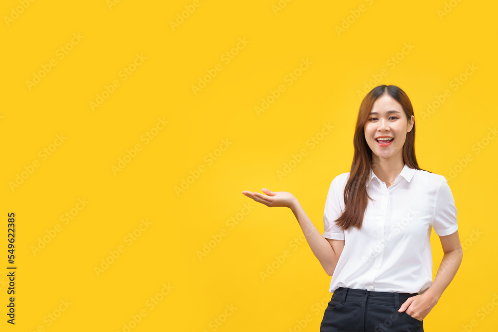 Women smiling and showing hand to presenting product with empty space on isolated yellow background Women smiling and showing hand to presenting product with empty space on isolated yellow background