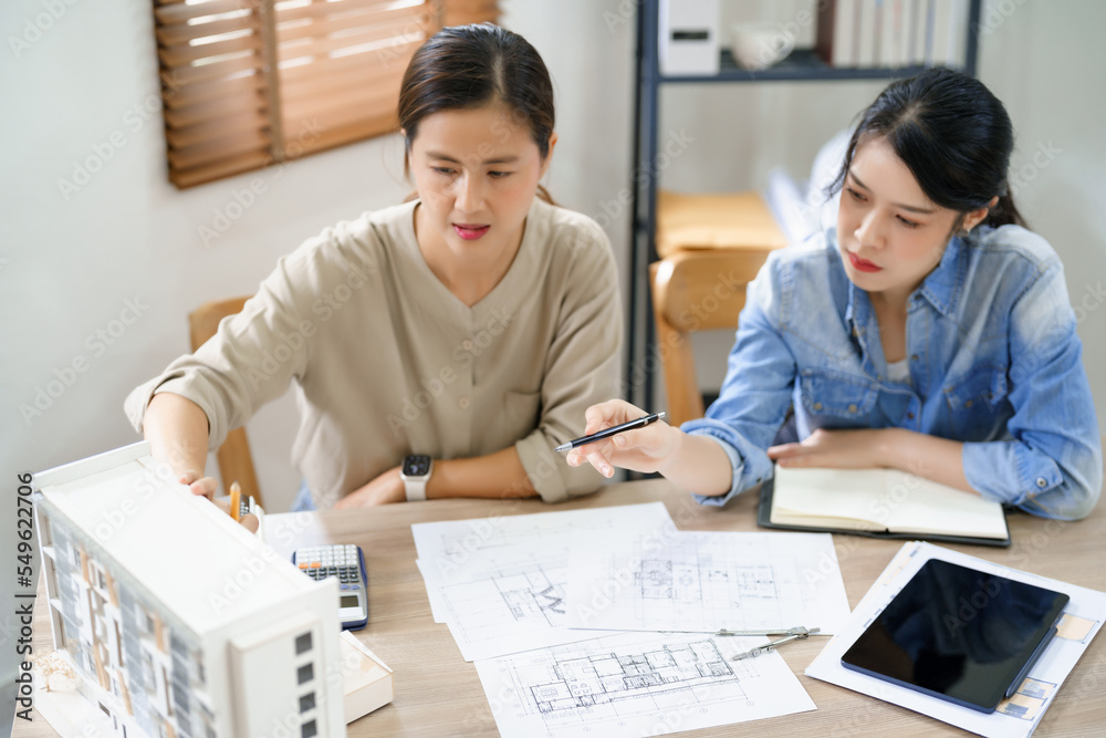 Engineering construction concept, Two female engineers pointing and discussing model of building Engineering construction concept, Two female engineers pointing and discussing model of building
