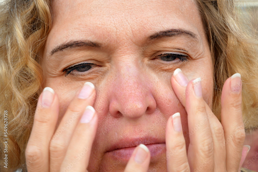 middle aged female's eye with drooping eyelid making facial massage