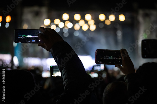 Concert being recorded by some people by their cellphones at night
