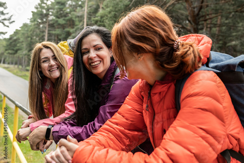 Portrait of a three women with a backpack talking in the nature. Friends hiking retreat. Focus on brunette woman  photo