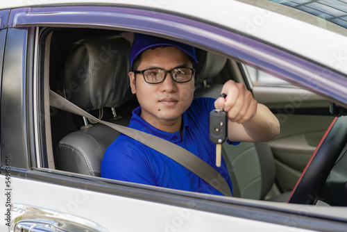 Handsome young man in a good mood holding the keys of a new car with a smile Asian man with car keys in hand The idea of ​​having a new car and buying and selling.